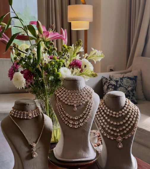 Three layered Indian necklace displays arranged with flowers in an elegant interior